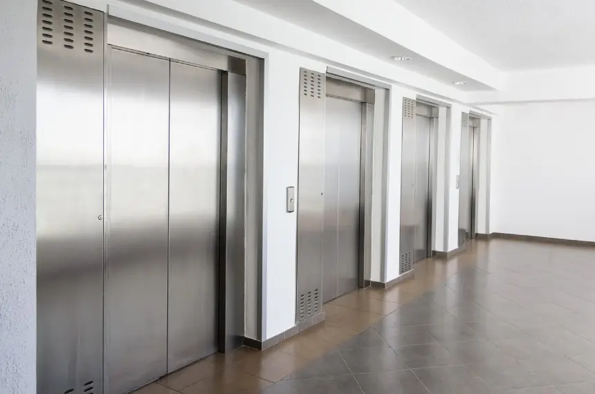A row of metal elevators in an office building.