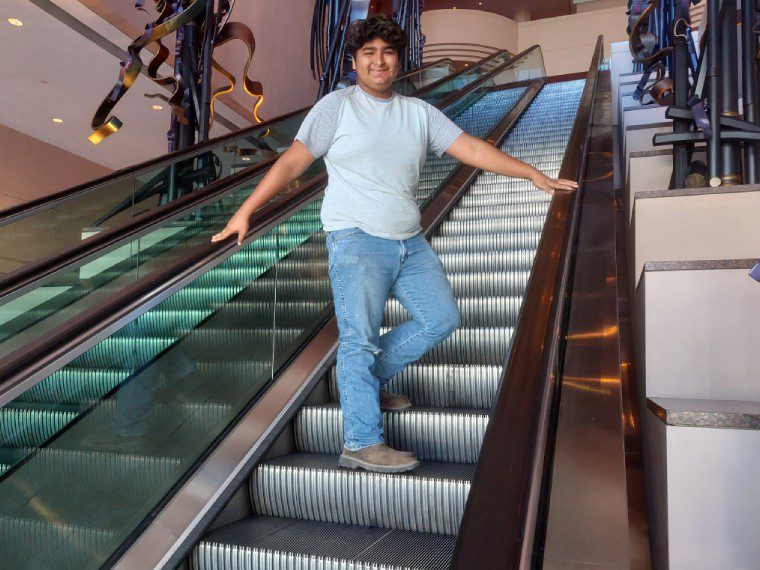 A woman standing on an escalator with her arms outstretched.